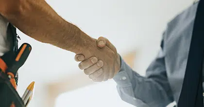 Handschlag zwischen Handwerker mit Werkzeuggürtel und Kunden im Hemd