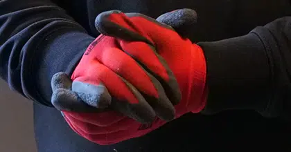 Ineinandergelegte Hände in rot-schwarzen Handwerker Handschuhen